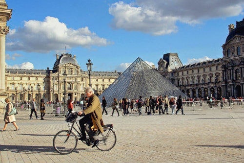Tudo sobre a Eurail | Idoso de bicicleta passando pelo Museu do Louvre em Paris, França